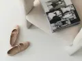 Eleganckie baleriny Ryłko na jasnym tle, obok otwarta książka. Dowiedz się, jak zmiękczyć buty na pięcie, by były idealnie dopasowane.