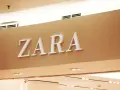ZARA, znana marka odzieżowa, prezentuje swoje logo na jasnobrązowej ścianie.