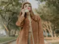 Kobieta w brązowej zamszowej kurtce damskiej rozmawia przez telefon w stylu retro.