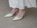 Eleganckie, kremowe szpilki z paskiem na pięcie, idealne do letnich sukienek. Niewidoczne skarpetki do szpilek zapewniają komfort.