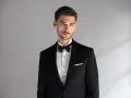 Elegancki mężczyzna w czarnym smokingu z białą poszetką. Dowiedz się, jak dobrać poszetkę do stylizacji.