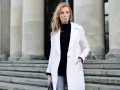 Elegancka kobieta w białym płaszczu i czarnym golfie, prezentująca stylowe biały płaszcz stylizacje na tle monumentalnych schodów.
