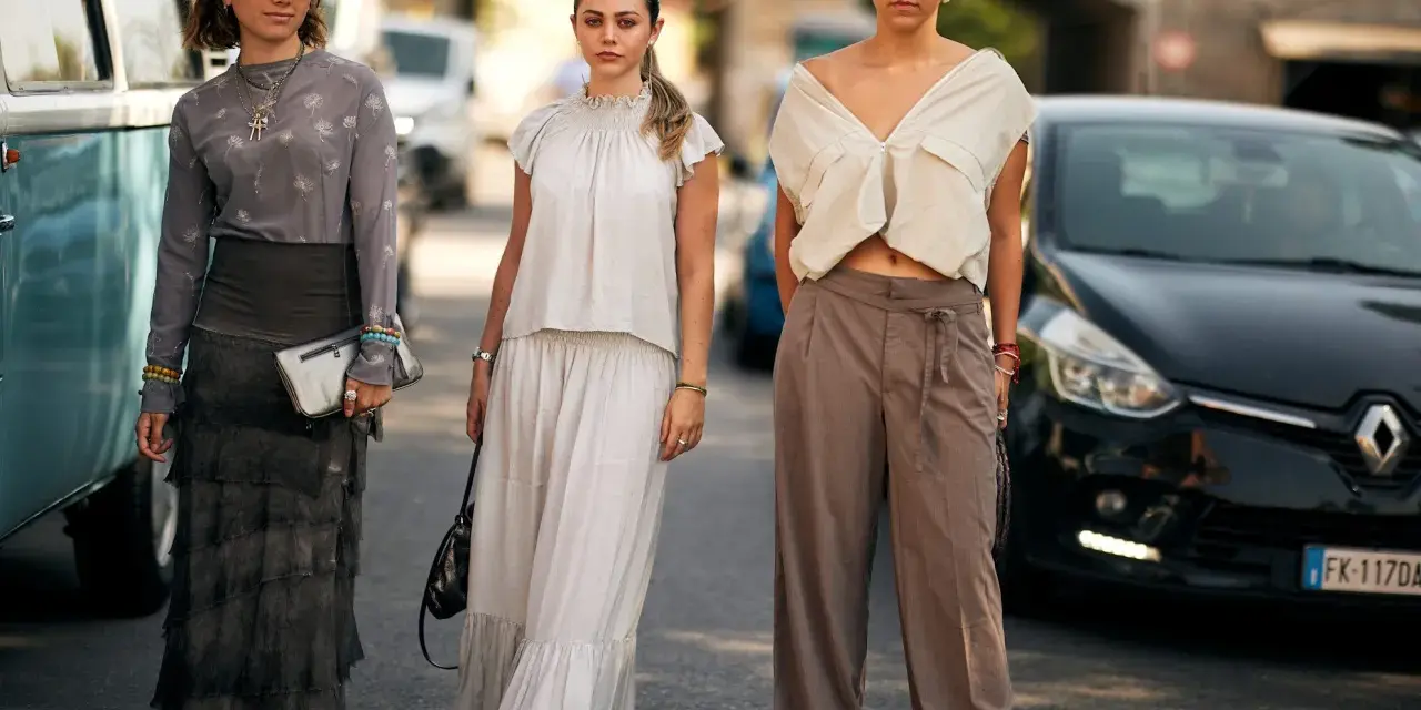 Trzy kobiety prezentują modne stylizacje damskie: jedna w długiej, falbaniastej spódnicy i wzorzystej bluzce, druga w lnianym komplecie, trzecia w szerokich spodniach i crop topie.