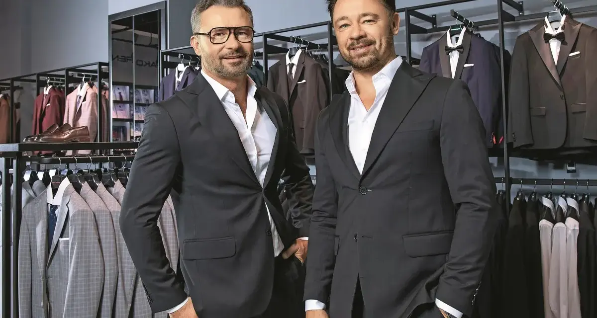 Dwóch eleganckich mężczyzn w garniturach, w sklepie z odzieżą męską. Czy to Pako Lorente czy Vistula?