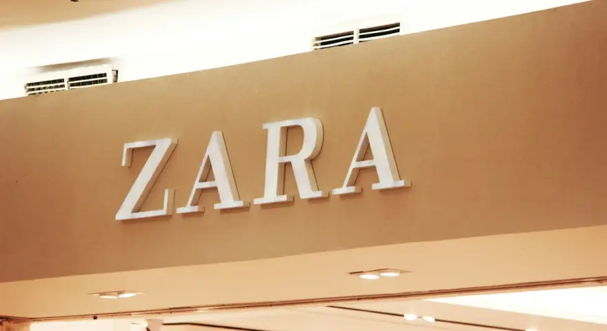 ZARA, znana marka odzieżowa, prezentuje swoje logo na jasnobrązowej ścianie.