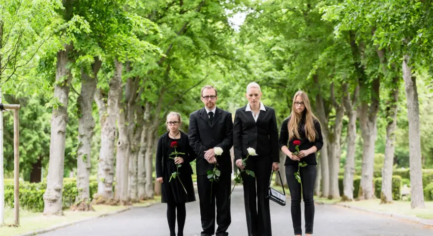 Rodzina w czarnych strojach, trzymająca róże, pokazuje, jak się ubrać na pogrzeb. Elegancko i z szacunkiem.