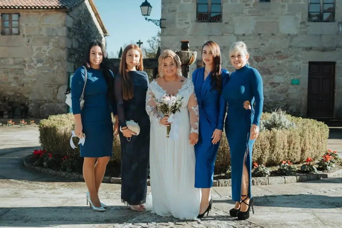 Pięć kobiet w niebieskich i granatowych sukienkach, panna młoda w bieli. Eleganckie buty do chabrowej sukienki podkreślają stylizację.