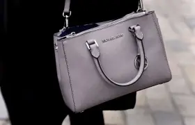 Szara torebka Michael Kors, znanej firmy z luksusowymi akcesoriami, z widocznym logo.